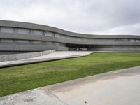 a building with cement roof near green grass and lawn in front of it, under a gray sky