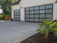 a large garage has sliding glass doors, and has green plants growing on the concrete and concrete