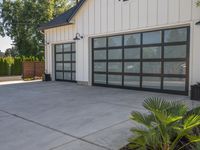 a large garage has sliding glass doors, and has green plants growing on the concrete and concrete