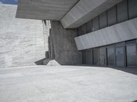 the empty courtyard near a large building with many glass doors on the floor and concrete wall walls