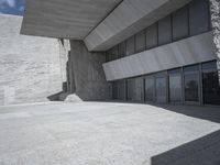 the empty courtyard near a large building with many glass doors on the floor and concrete wall walls