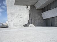 the empty courtyard near a large building with many glass doors on the floor and concrete wall walls