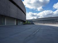 a concrete building sitting on a concrete surface next to a parking lot with several garages