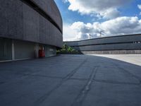 a concrete building sitting on a concrete surface next to a parking lot with several garages