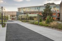 a city street surrounded by grass and tall buildings at the end of a street there is a paved pathway in front of the building