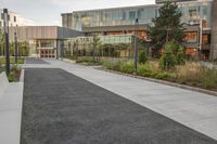 a city street surrounded by grass and tall buildings at the end of a street there is a paved pathway in front of the building