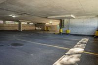 a parking garage with yellow painted lines and windows on the inside of the area, with grey walls and a large concrete ceiling