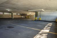 a parking garage with yellow painted lines and windows on the inside of the area, with grey walls and a large concrete ceiling