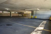 a parking garage with yellow painted lines and windows on the inside of the area, with grey walls and a large concrete ceiling