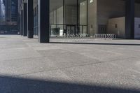 there are many bike racks in the middle of a sidewalk and walkway, with an office building behind them