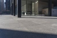 there are many bike racks in the middle of a sidewalk and walkway, with an office building behind them