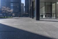 there are many bike racks in the middle of a sidewalk and walkway, with an office building behind them