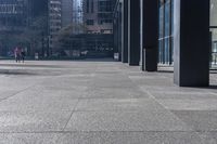 there are many bike racks in the middle of a sidewalk and walkway, with an office building behind them