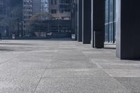 there are many bike racks in the middle of a sidewalk and walkway, with an office building behind them