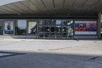 a person sitting at the bench in front of a mall that is empty of people