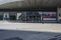 a person sitting at the bench in front of a mall that is empty of people