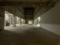 a concrete floor in a room next to an empty garage area with a light on