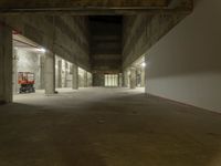 a concrete floor in a room next to an empty garage area with a light on