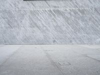 the skateboarder does a trick on the concrete floor of a skate park while wearing sunglasses