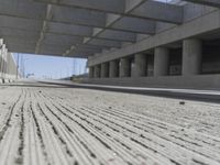 a concrete garage with large columns and a concrete wall and road area in the background