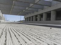 a concrete garage with large columns and a concrete wall and road area in the background