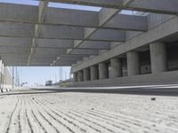 a concrete garage with large columns and a concrete wall and road area in the background