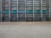 an industrial concrete building has several scaffolding in front of it, with steel pipes and steel bars