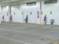 three men are charging their electric vehicles at an electric car park in a building,