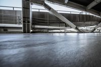 a skate board is on the concrete floors in a parking garage area and some stairs in the background