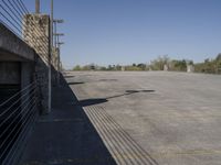 a concrete parking lot, which has a stone wall with iron bars and a red traffic light