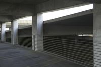 large concrete pillars in an empty parking garage area with a long wire rail railing running under them
