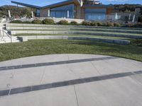 a concrete skateboard ramp going up the side of a hill by some stairs in front of a house