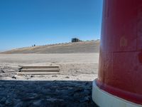 red fire extinguistor in open field by mountain side with steps to it