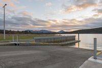 the bridge is on the edge of the lake near water and mountains in the background