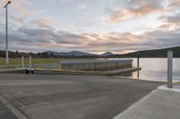 the bridge is on the edge of the lake near water and mountains in the background