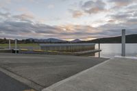 the bridge is on the edge of the lake near water and mountains in the background