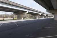 empty parking space under a large concrete road overpassing the road and overhead street