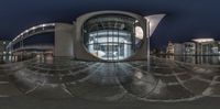 the 360 panoramic photo shows the circular entrance to an outside building next to water