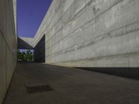 a concrete sidewalk and concrete walls near an opening on top of the building to allow people to access the space