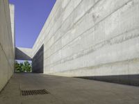 a concrete sidewalk and concrete walls near an opening on top of the building to allow people to access the space