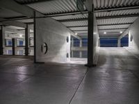 a dimly lit parking garage, showing the ground, ceiling and lights in it, all by itself