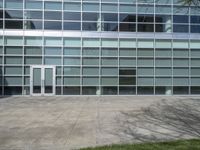 two glass doors in front of an office building with trees and grass nearby on a sunny day