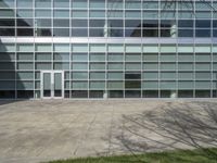 two glass doors in front of an office building with trees and grass nearby on a sunny day