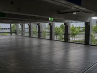 a parking garage with metal floors and walls, looking into some trees below the ceiling