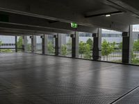 a parking garage with metal floors and walls, looking into some trees below the ceiling