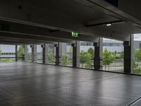 a parking garage with metal floors and walls, looking into some trees below the ceiling