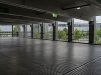 a parking garage with metal floors and walls, looking into some trees below the ceiling