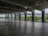 a parking garage with metal floors and walls, looking into some trees below the ceiling