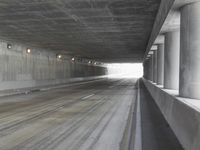 a city street is seen in a tunnel of an overpassing area with columns