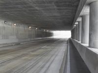 a city street is seen in a tunnel of an overpassing area with columns